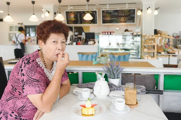 Asijské starší žena stawberry tvarohový dort v kavárně. — Stock fotografie
