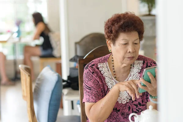 Азиатская старшая женщина использует смартфон в кафе . — стоковое фото