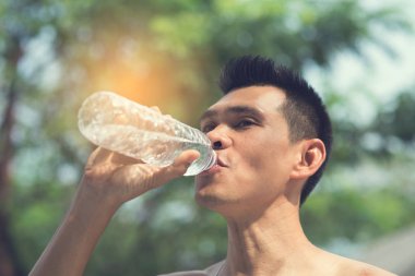 Bir şişe su bokeh arka plan ile içme spor adam üstün