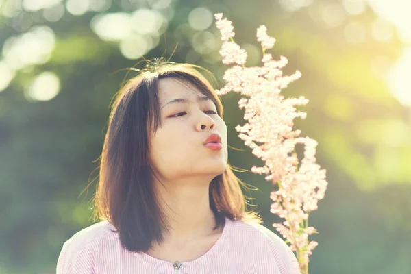 Ázsiai nő fúj üveg virágot a napfény, a természetben. — Stock Fotó
