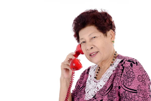 Asian senior woman talking on red vintage phone. — Stock Photo, Image