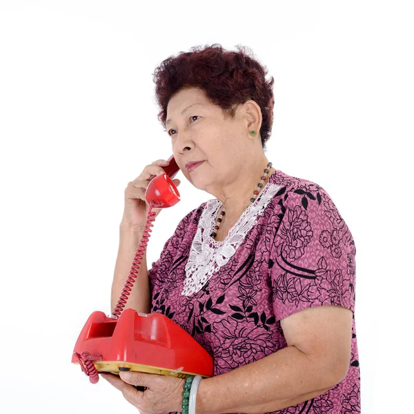 Asijské starší žena mluví o červené vintage telefonu. — Stock fotografie