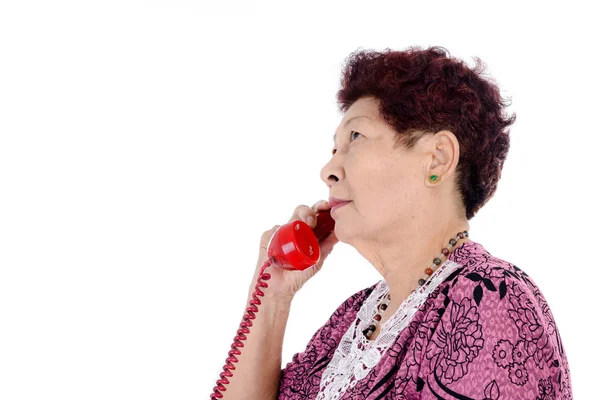 Asian senior woman talking on red vintage phone. — Stock Photo, Image