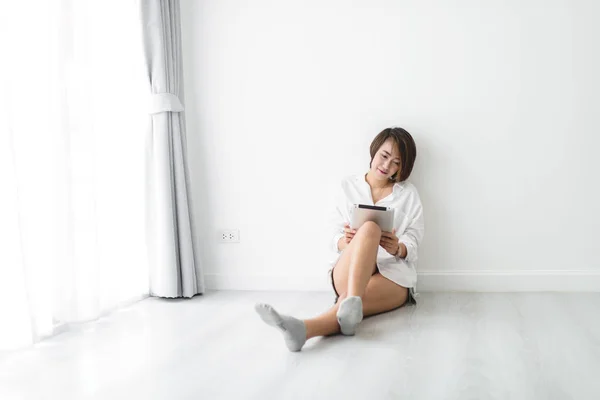 Schöne junge asiatische Frau trägt weißes Hemd und verwendet Tablette — Stockfoto