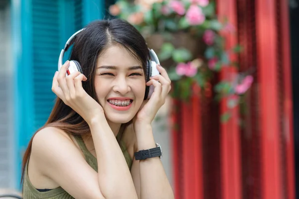Heureuse femme asiatique écoutant de la musique avec fond de couleur outdo — Photo