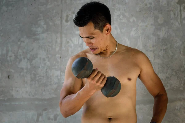 Un hombre musculoso y sudoroso está entrenando en el gimnasio levantando el —  Fotos de Stock