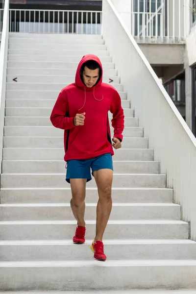 Homem do esporte em capuz vermelho correndo para baixo em passos, borrão de movimento . — Fotografia de Stock