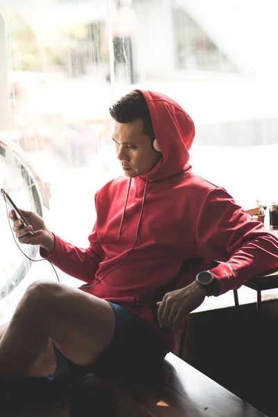 Sport muž v poslechu hudby pomocí chytrého telefonu, moderní Červená Karkulka — Stock fotografie