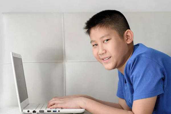 Asiatiska boy handpåläggning soffa och använder bärbar dator hemma. — Stockfoto