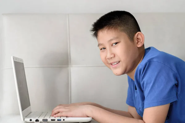 Asiático menino deitado no sofá e usando laptop em casa . — Fotografia de Stock