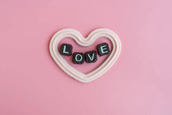 White chocolate in heart shape with message love on pink backgro — Stock Photo, Image