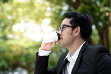 Mutlu işadamı kahve fincanı doğa arka plan ile içme. L