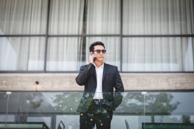 Backgro bina ile telefon ile konuşurken akıllı Asya iş adamı