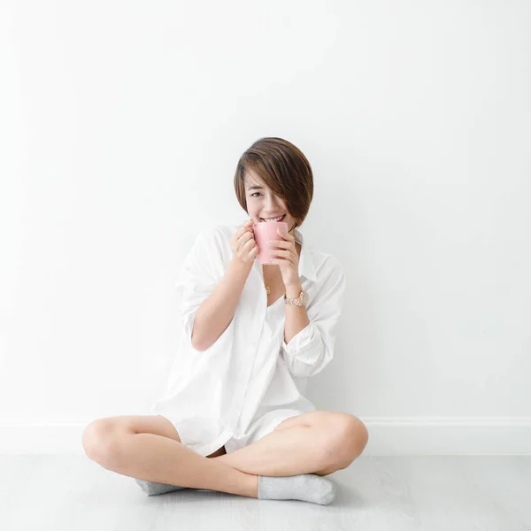 Mujer asiática feliz vistiendo camisa blanca sosteniendo taza rosa en blanco — Foto de Stock