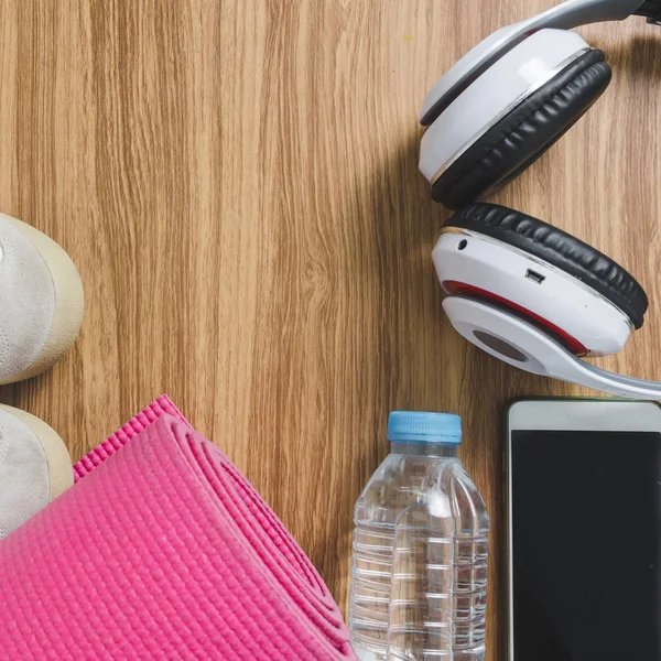 Auriculares para esterilla de yoga, zapatos deportivos, una botella de agua y un teléfono inteligente —  Fotos de Stock