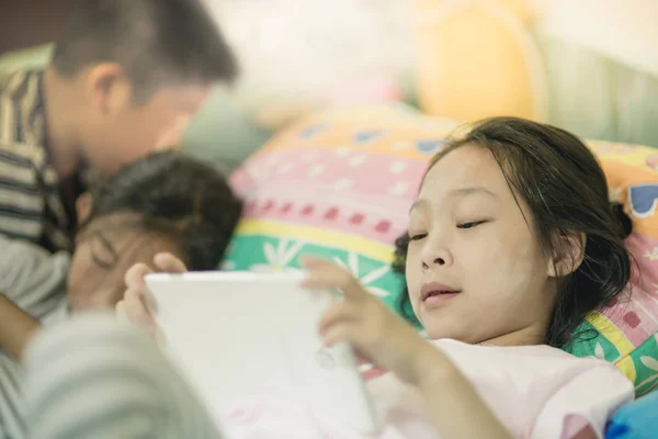 Enfants utilisant un téléphone intelligent et une tablette au lit à la maison, mode de vie — Photo