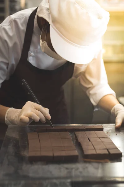 Шеф-повар режет домашний шоколад на кухне . — стоковое фото