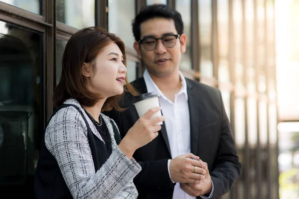 Kahve fincanı tutarak ve ekibi ile konuşurken iş kadını.