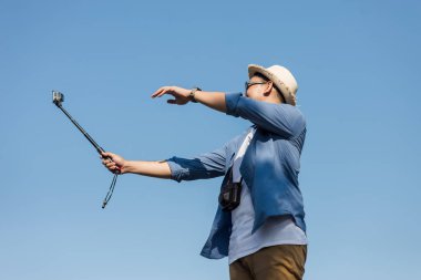 Mavi sk ile fotoğraf çekme kamera stick kullanarak mutlu Asya turizm