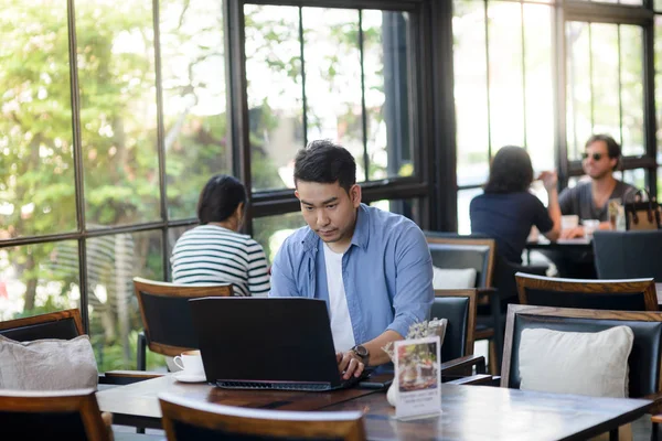 Hombre asiático trabajando con el ordenador portátil en la cafetería, concepto de trabajo . —  Fotos de Stock