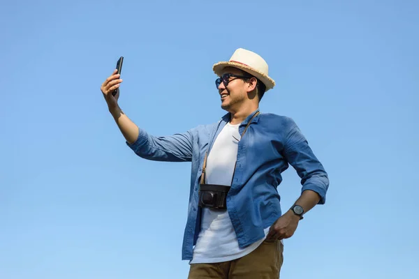 Happy Asian tourist using smartphone selfie himself with blue sk — Stok Foto