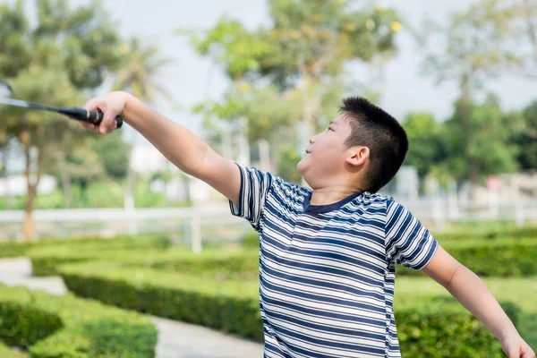 Feliz Asiang chico jugando bádminton al aire libre, desenfoque de movimiento . — Foto de Stock