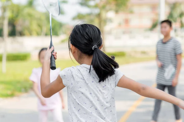 Desfoque de movimento de volta da menina jogando badminton com amigo ao ar livre . — Fotografia de Stock