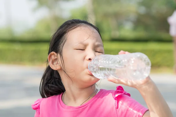 Happy Asian girl drinking a bottle of water outdoor. — Stock Photo, Image