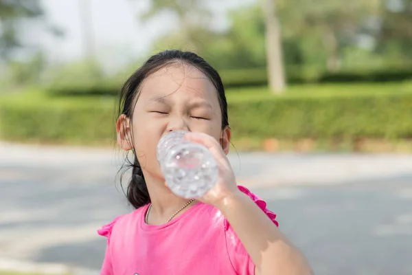 Happy Asian girl drinking a bottle of water outdoor. — Stock Photo, Image