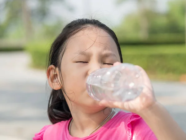 Gelukkig Aziatisch meisje, drinken van een fles water buiten. — Stockfoto