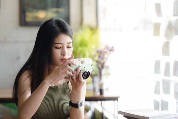 Happy Asian woman holding vintage camera in cafe, lifestyle conc