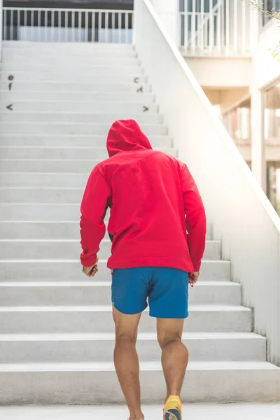 Rücken des Sportlers in roter Kapuze, der an Stufen hochläuft, Bewegungsunschärfe. — Stockfoto