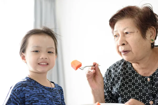 Büyükanne ile olgun papaya çocuğunu besleme dilimlenmiş. — Stok fotoğraf