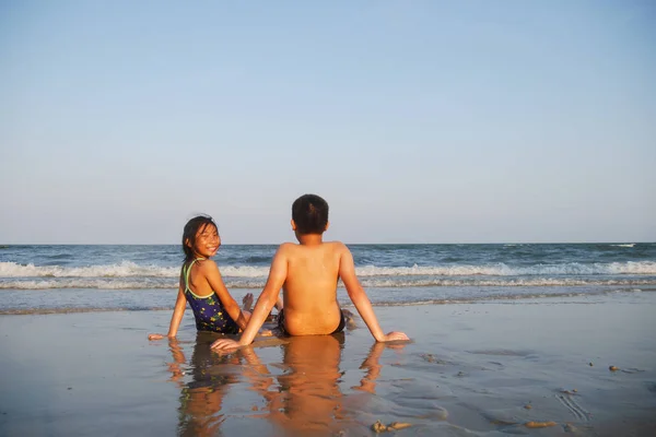 Šťastné děti, které sedí na pláži Hua Hin ve slunečný den. — Stock fotografie