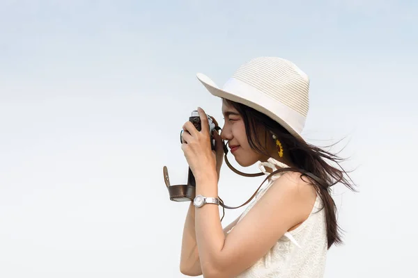 Mulher bonita tirando foto com câmera vintage na praia . — Fotografia de Stock