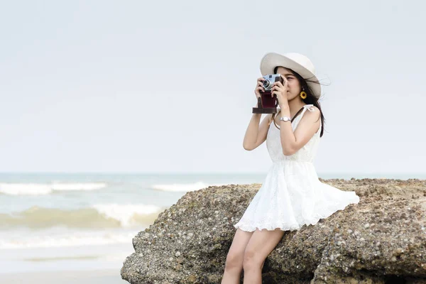 Bella donna scattare foto con fotocamera vintage sulla spiaggia . — Foto Stock