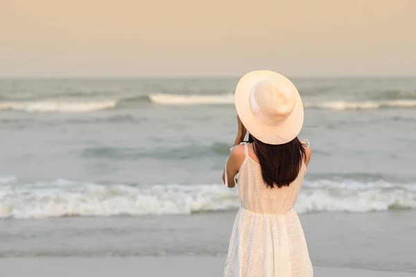 Indietro della donna che indossa cappello con abito bianco scattare foto sul b — Foto Stock
