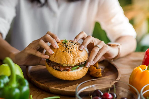 Mulher segurando hambúrguer de carne no restaurante . — Fotografia de Stock