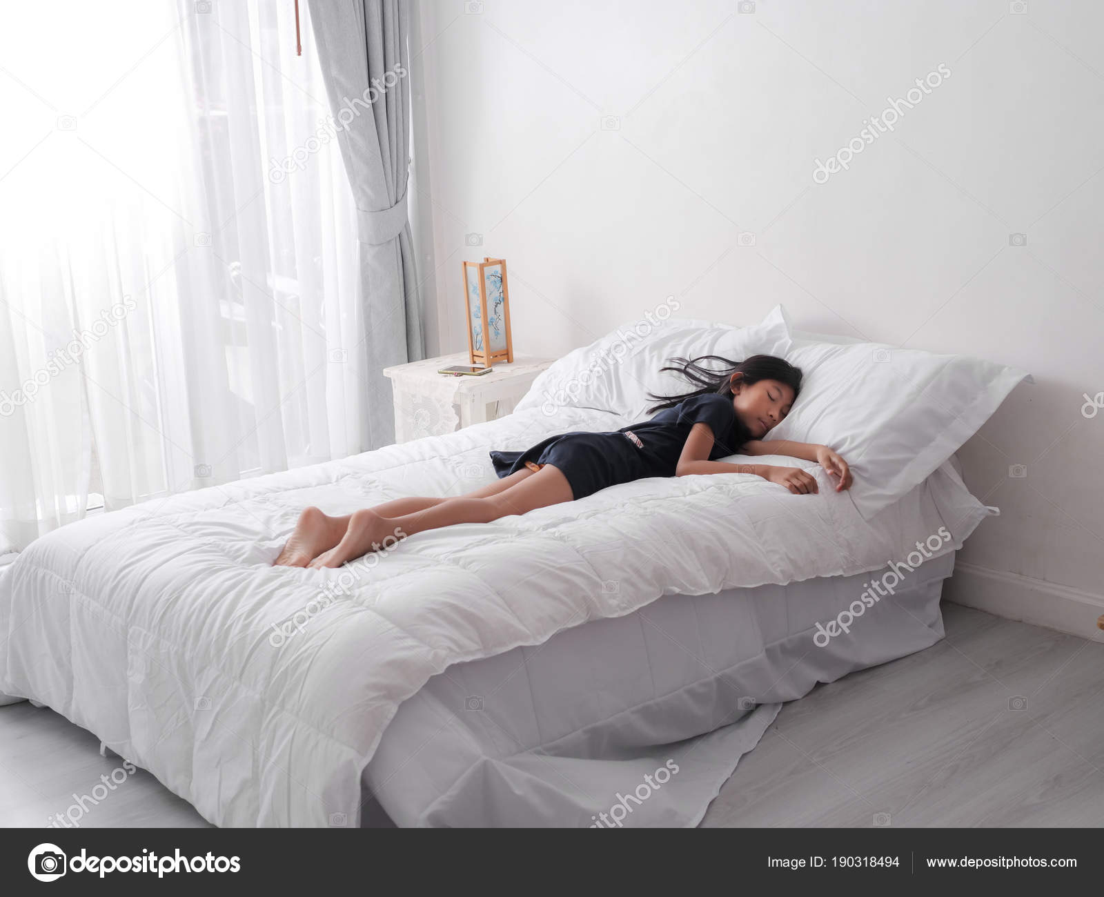 Girl sleeping on bed on bed in white home. Stock Photo by ©Jayjaynaenae