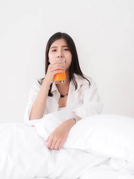 Wanita Asia bahagia minum jus jeruk di tempat tidur di akhir pekan — Stok Foto