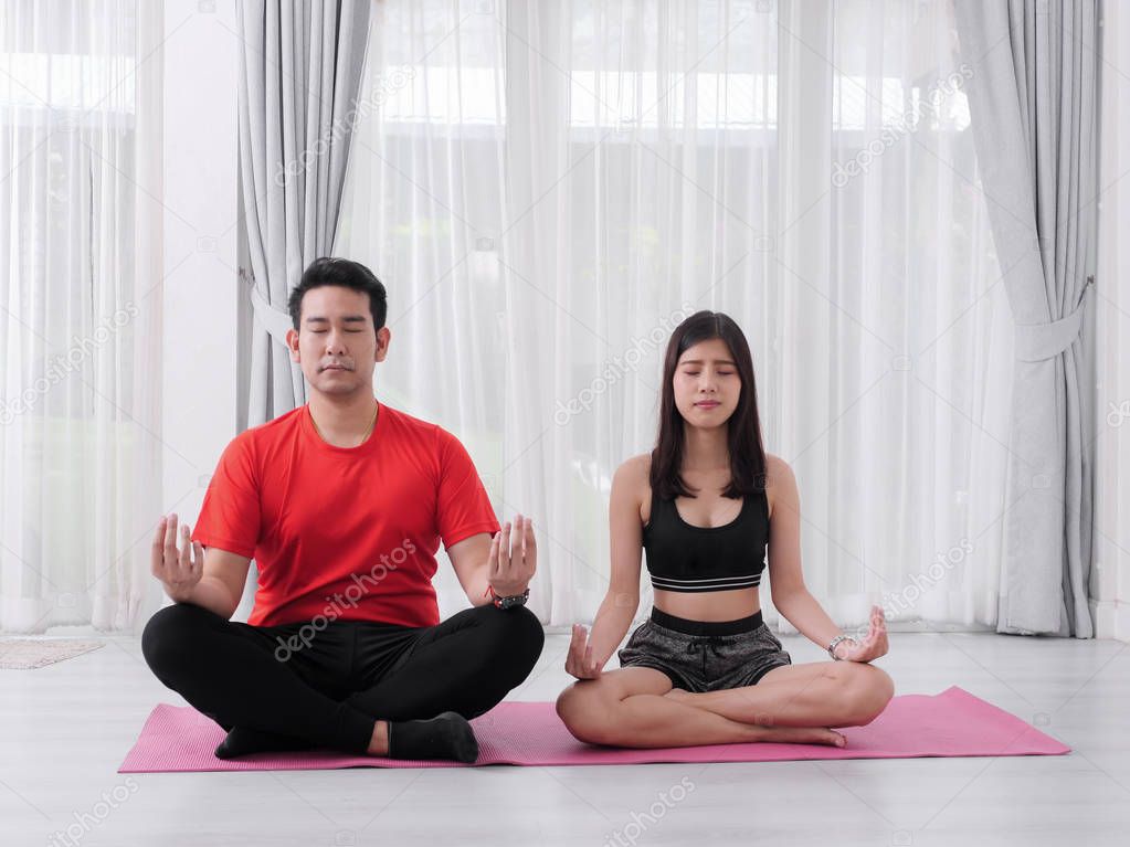 Happy couple making meditation at home together.