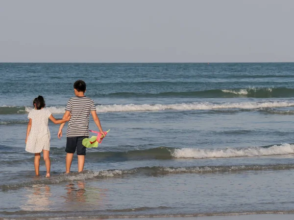 Back of children holding standing in the wave, boy holding green — Stock Photo, Image