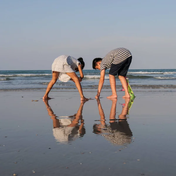 Asiatico ragazzo e ragazza in cerca di conchiglia sulla spiaggia, stile di vita estivo — Foto Stock