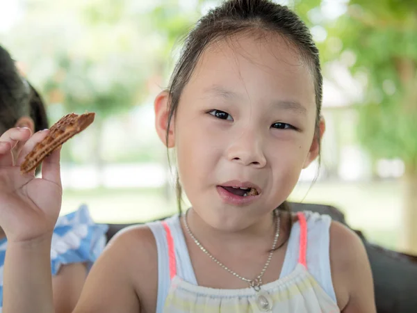 Felice ragazza asiatica mangiare waffle con la famiglia nel parco — Foto Stock