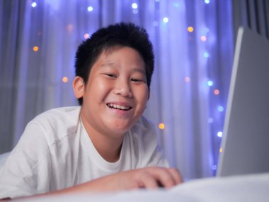 Mutlu varoluş çocuk Noel ışık backg ile yatağa dizüstü bilgisayar kullanarak