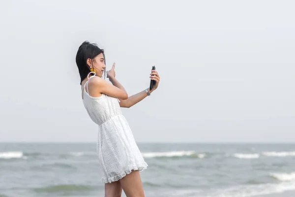 Happy asijské turistické selfie sama s smartphone na pláži. — Stock fotografie