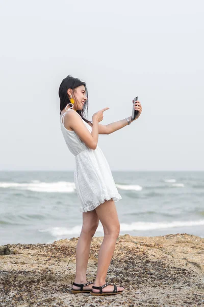 แฮปปี้เอเชียนักท่องเที่ยวเซลฟี่ตัวเองกับสมาร์ทโฟนบนชายหาด . — ภาพถ่ายสต็อก