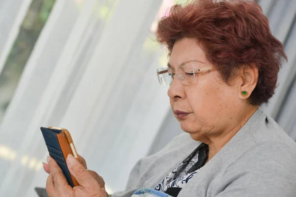 Szczęśliwy Asian kobieta senior w domu przy użyciu smartfona. — Zdjęcie stockowe