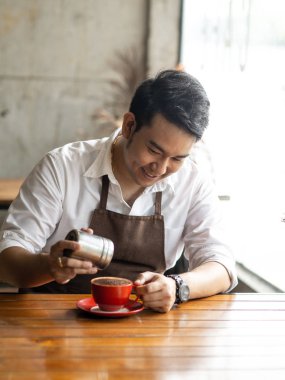 Asyalı barmen kırmızı bardağa çikolata tozu serper..
