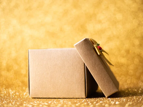Brązowe pudełko na tle złotego brokatu. — Zdjęcie stockowe